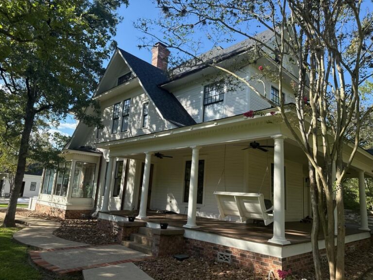 Wraparound porch with freshly painted columns, railings and soffit on a white two-storey home