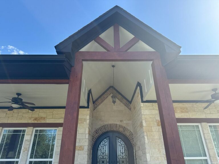 Stone and timber gable entry with dark painted columns and trim on a custom Texas home